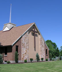 Brown brick and stone building with large cross on outside wall
